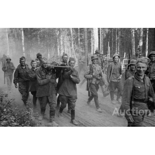 Пленные красноармейцы несут на носилках раненого товарища под конвоем финских солдат
