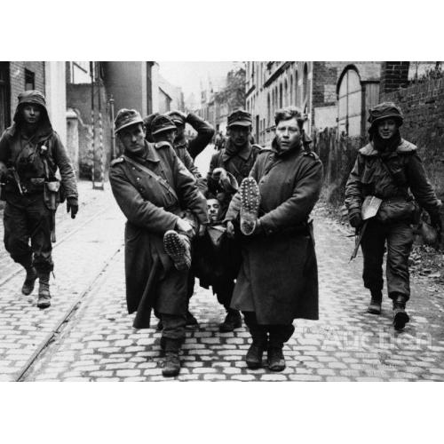 Пленные немецкие солдаты несут раненного товарища на улице Кобленца